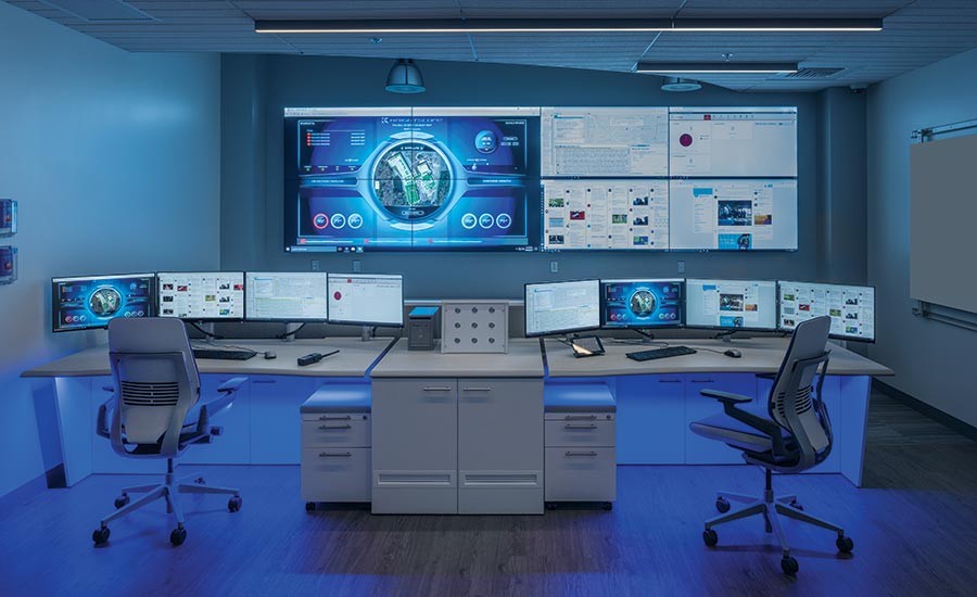 GSOC analyst at workstation with monitor wall